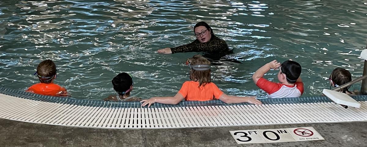Swim Lesson instructor teaching front crawl arms to five students